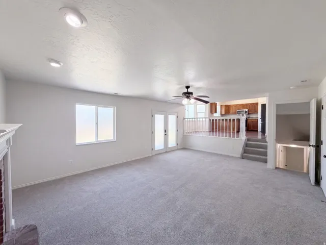 Recessed ceiling lighting, ceiling fan, white paneled double doors, white window trim, and a fireplace with a white mantel