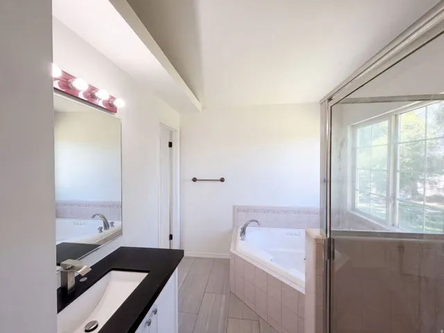 Vanity with dark countertop, undermount sink, and contemporary faucet