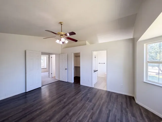 Vaulted ceiling with a ceiling fan, wood-finish flooring, and white interior doors
