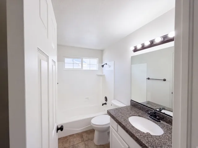 Bathroom featuring a white vanity with a speckled countertop, integrated sink, and a dark-toned faucet
