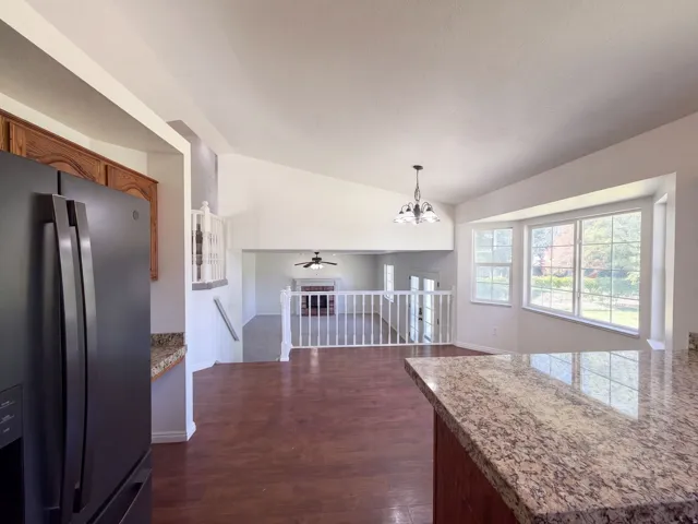 Vaulted ceilings, wood-finish flooring, bay window, granite-style countertops, and white railing