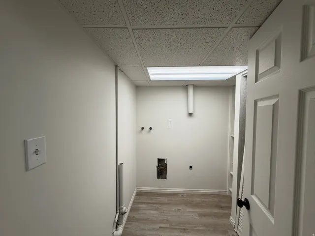 Utility room featuring wood-finish flooring, white walls, and a drop ceiling
