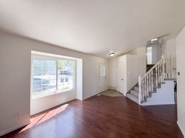 Hardwood-finish flooring, white trim, a multi-pane window, and a carpeted staircase with white railings