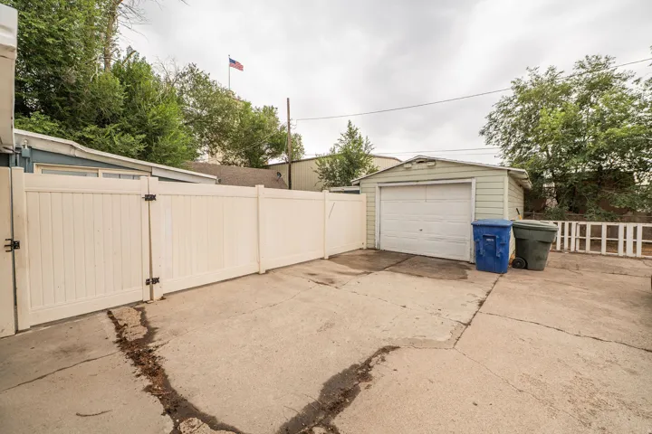 Detached garage with roll-up door, concrete driveway, and privacy fencing