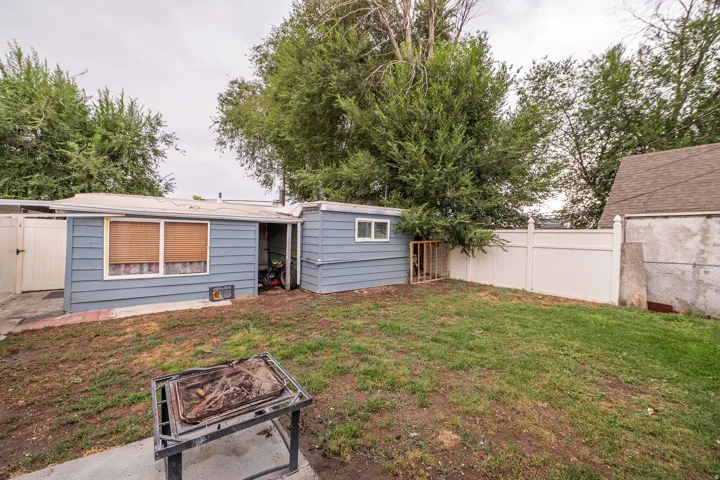 Expansive backyard featuring a partial vinyl fence and mature trees