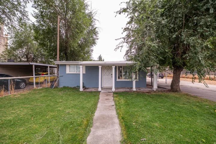 Single-story residence with a blue exterior and white trim, featuring a covered porch with white columns and a front yard with a concrete pathway