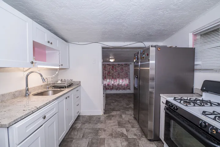 White cabinetry, light-toned countertops, stainless steel appliances, and a gas range