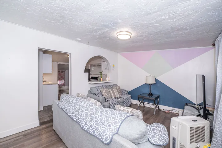 Wood-finish flooring, recessed ceiling lighting, arched pass-through window, and a geometric accent wall
