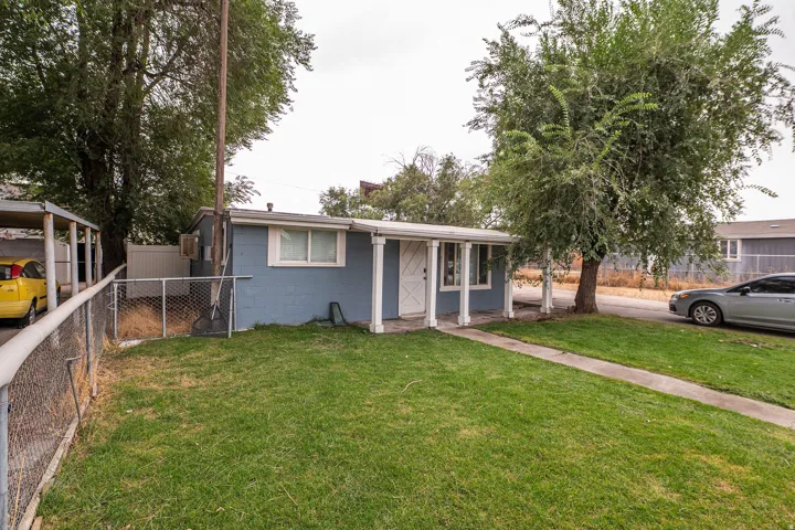 Front yard featuring a manicured lawn, established trees, and a concrete pathway leading to the covered porch