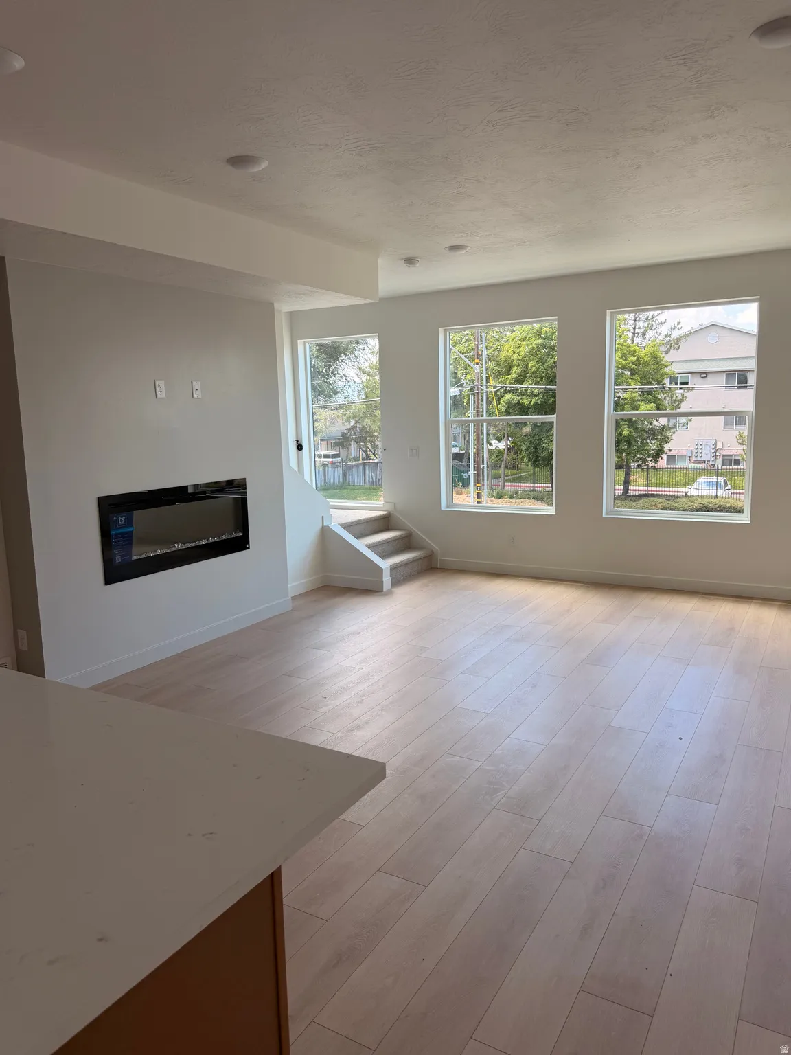 Spacious interior with wood-finish flooring, recessed lighting, and an integrated electric fireplace