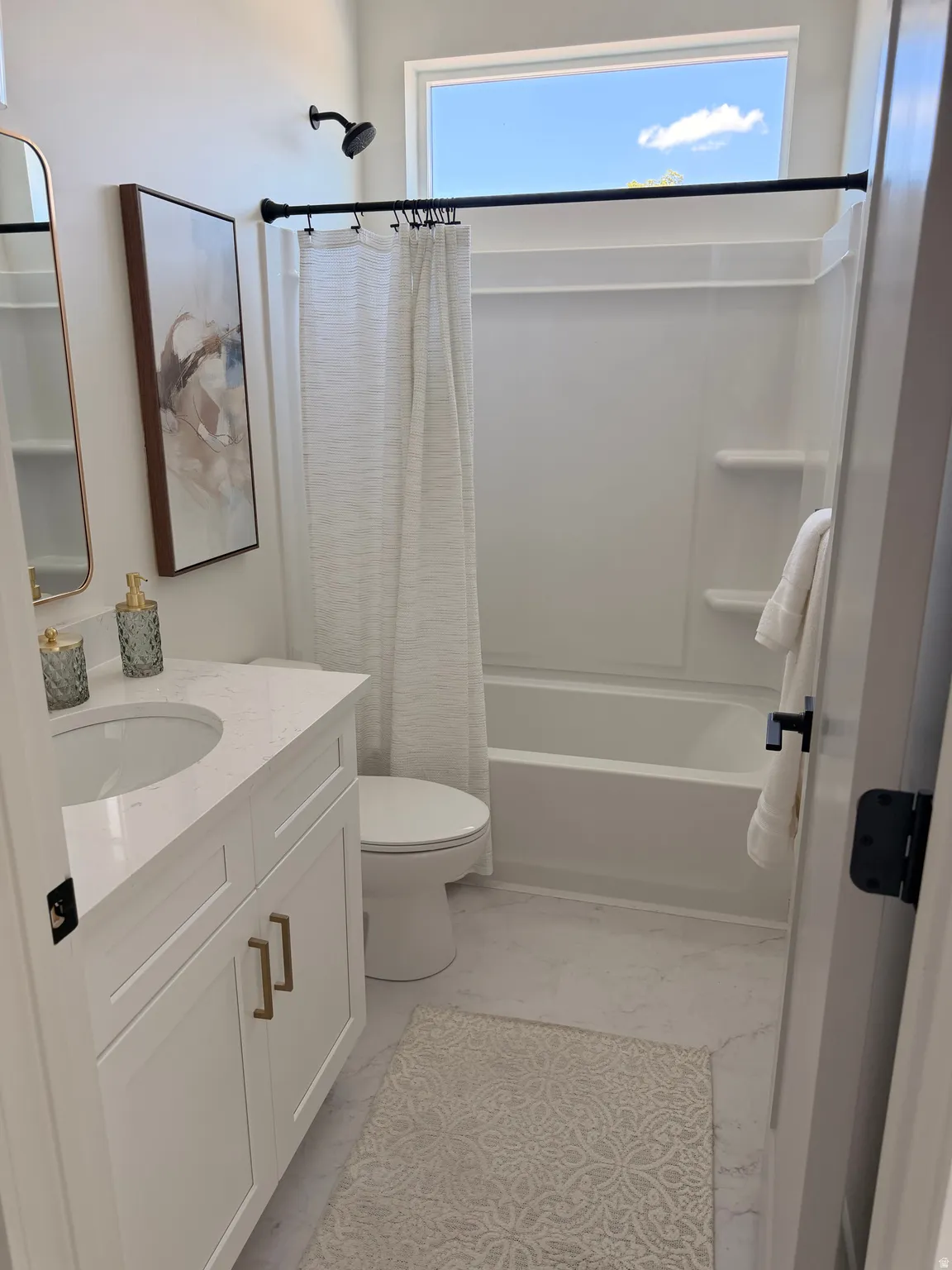 White vanity with gold-tone hardware, undermount sink, and light-toned countertop