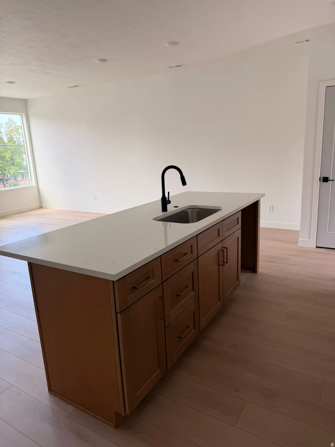 Kitchen island with a light-toned countertop, integrated sink, and matte black faucet