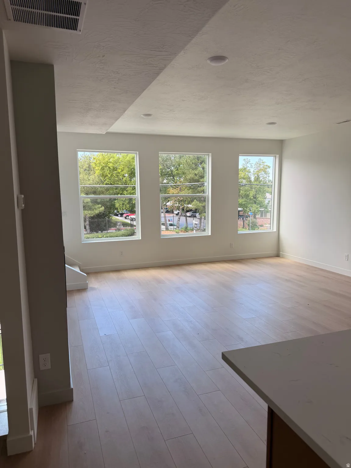 Expansive living area featuring light wood-finish flooring, recessed lighting, and multiple windows