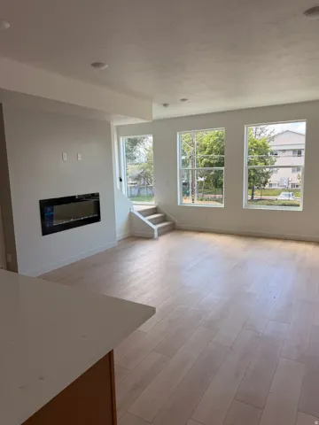 Spacious interior with wood-finish flooring, recessed lighting, and an integrated electric fireplace