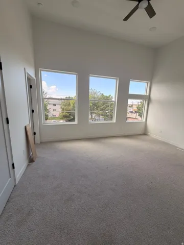 Vaulted ceiling, multiple windows, recessed lighting, ceiling fan, and light-toned carpeting