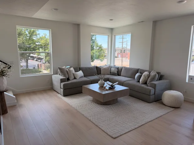 Recessed lighting, wood-finish flooring, multiple large windows, and clean white walls create a bright interior