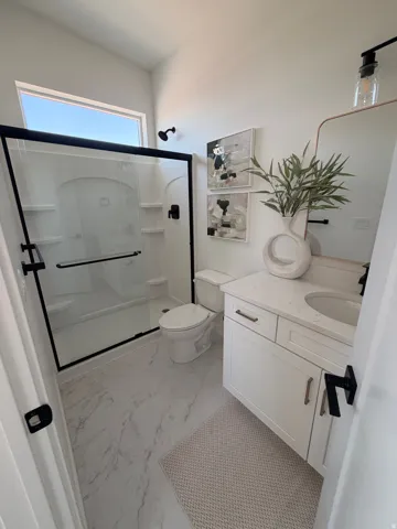 White shaker vanity with a stone-finish countertop and undermount sink