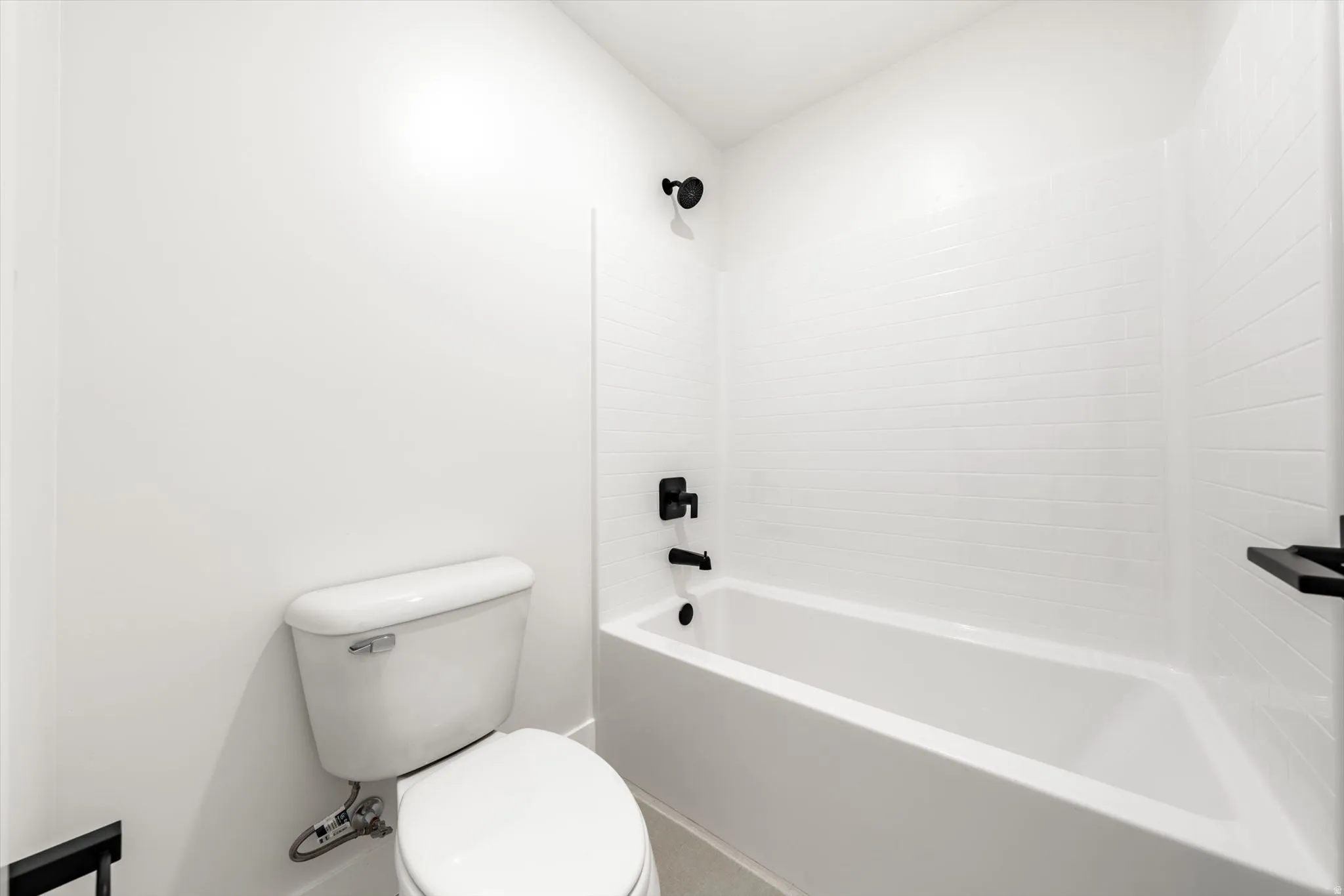 White subway tile tub surround, matte black fixtures, and a white toilet