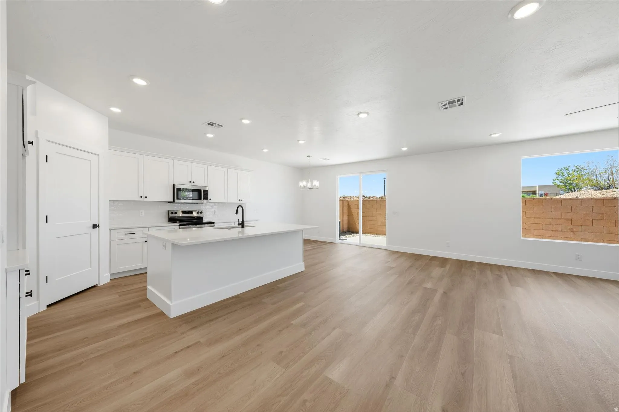 Open-concept living area featuring wood-finish flooring, recessed lighting, and a modern kitchen