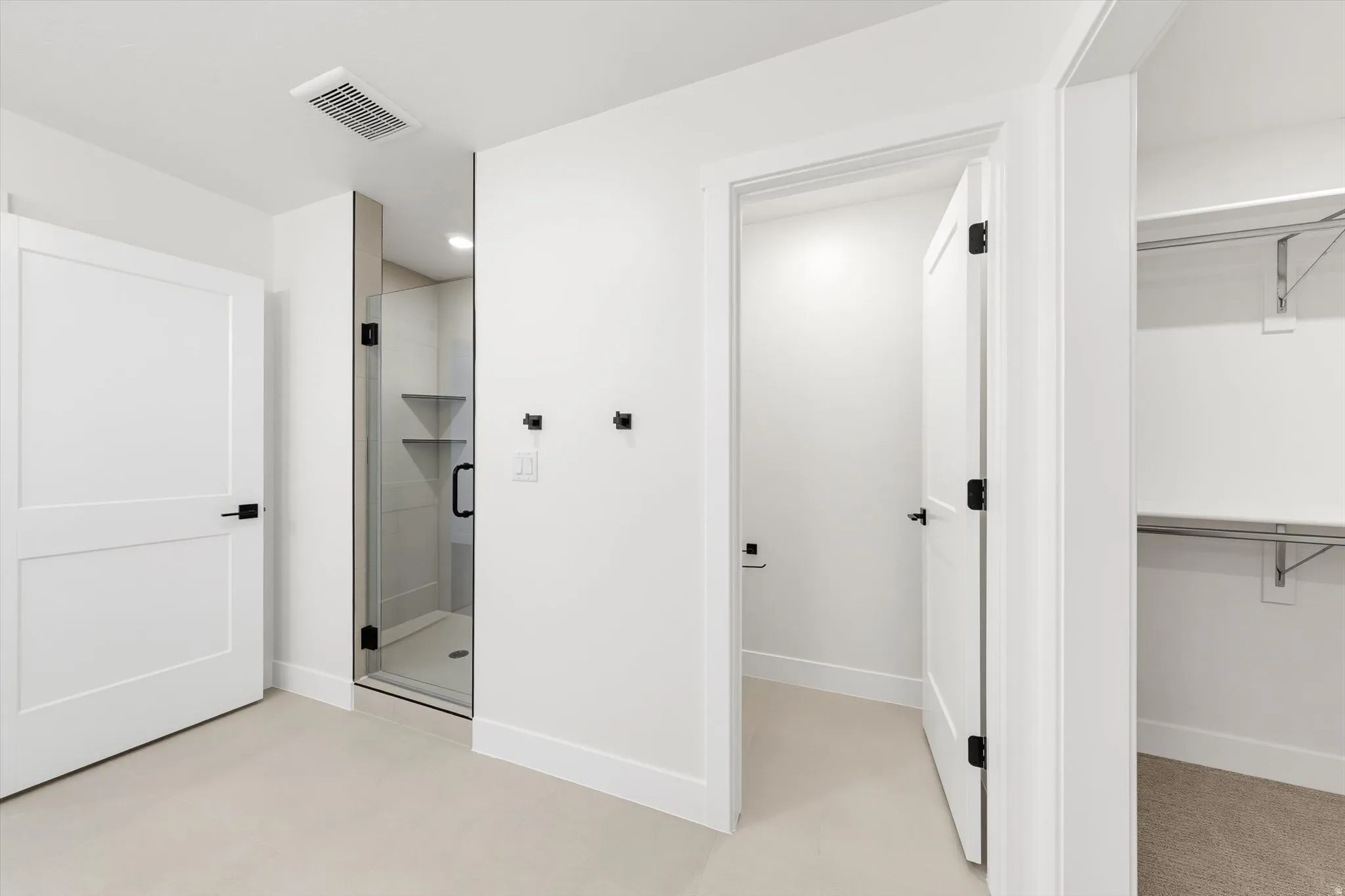 Glass-enclosed shower with dark hardware and built-in shelving