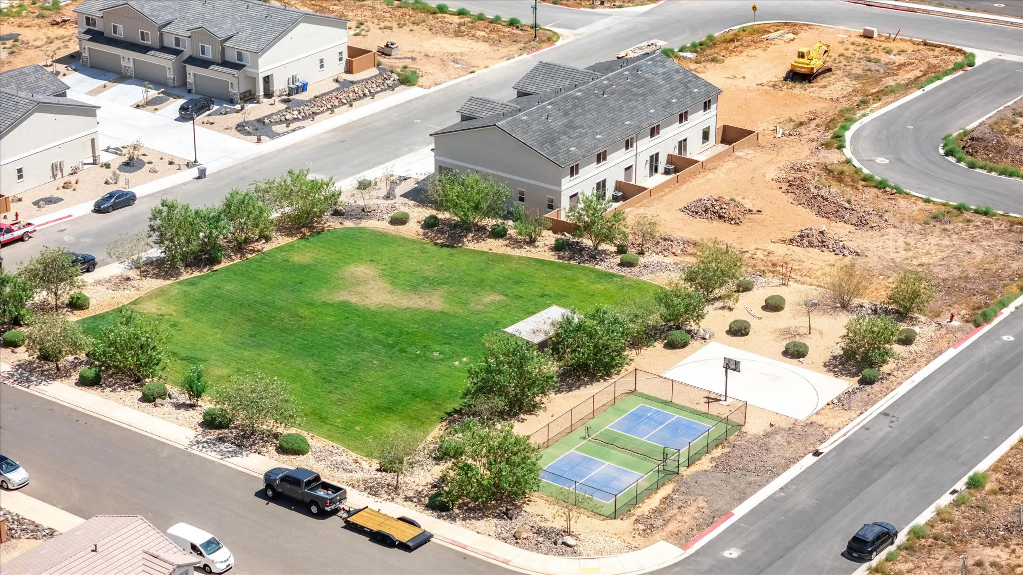 Green space with a manicured lawn, paved pickleball courts, and a half-court basketball area