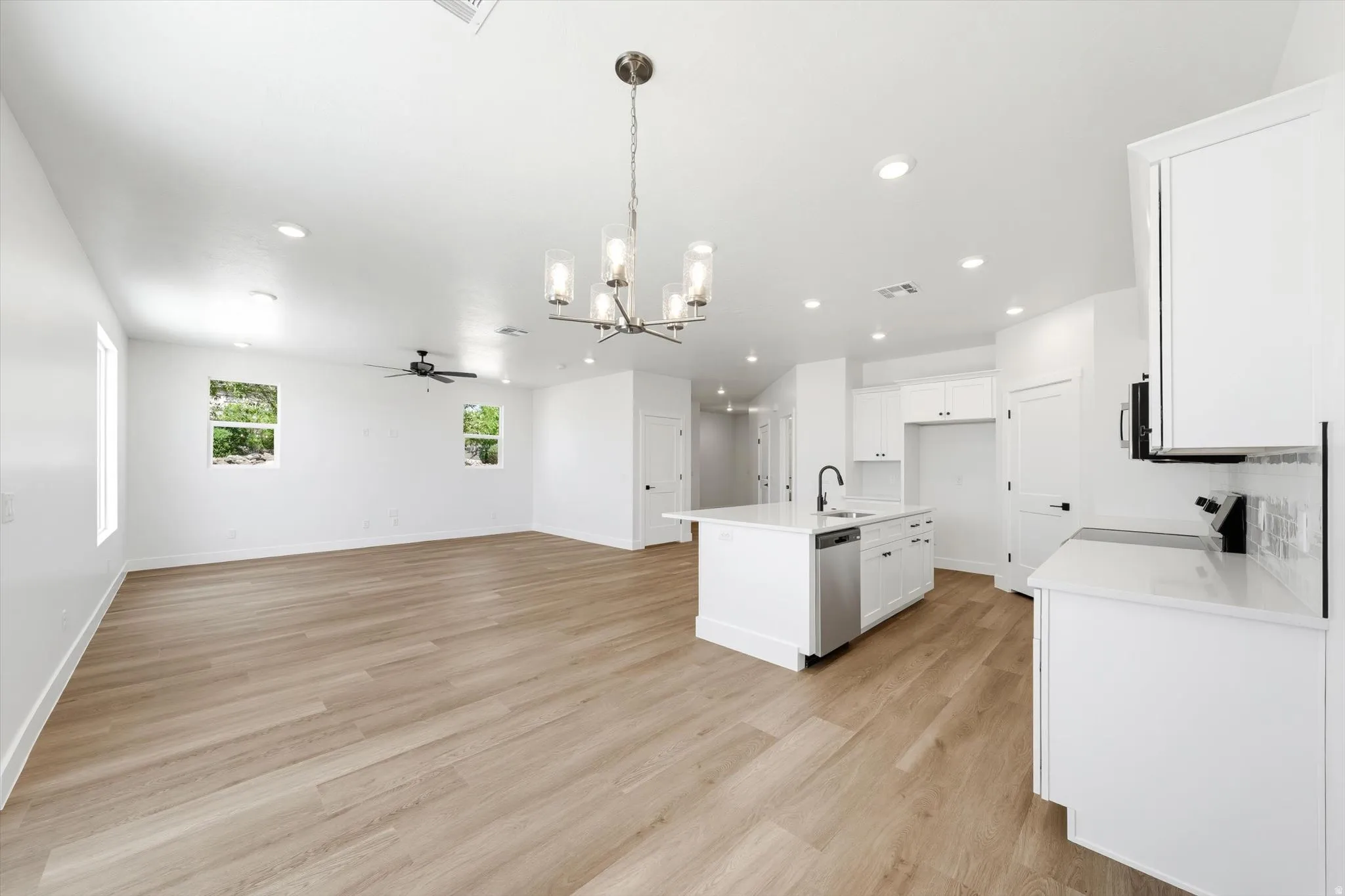 Open-concept living space with wood-finish flooring, recessed lighting, a ceiling fan, and white walls