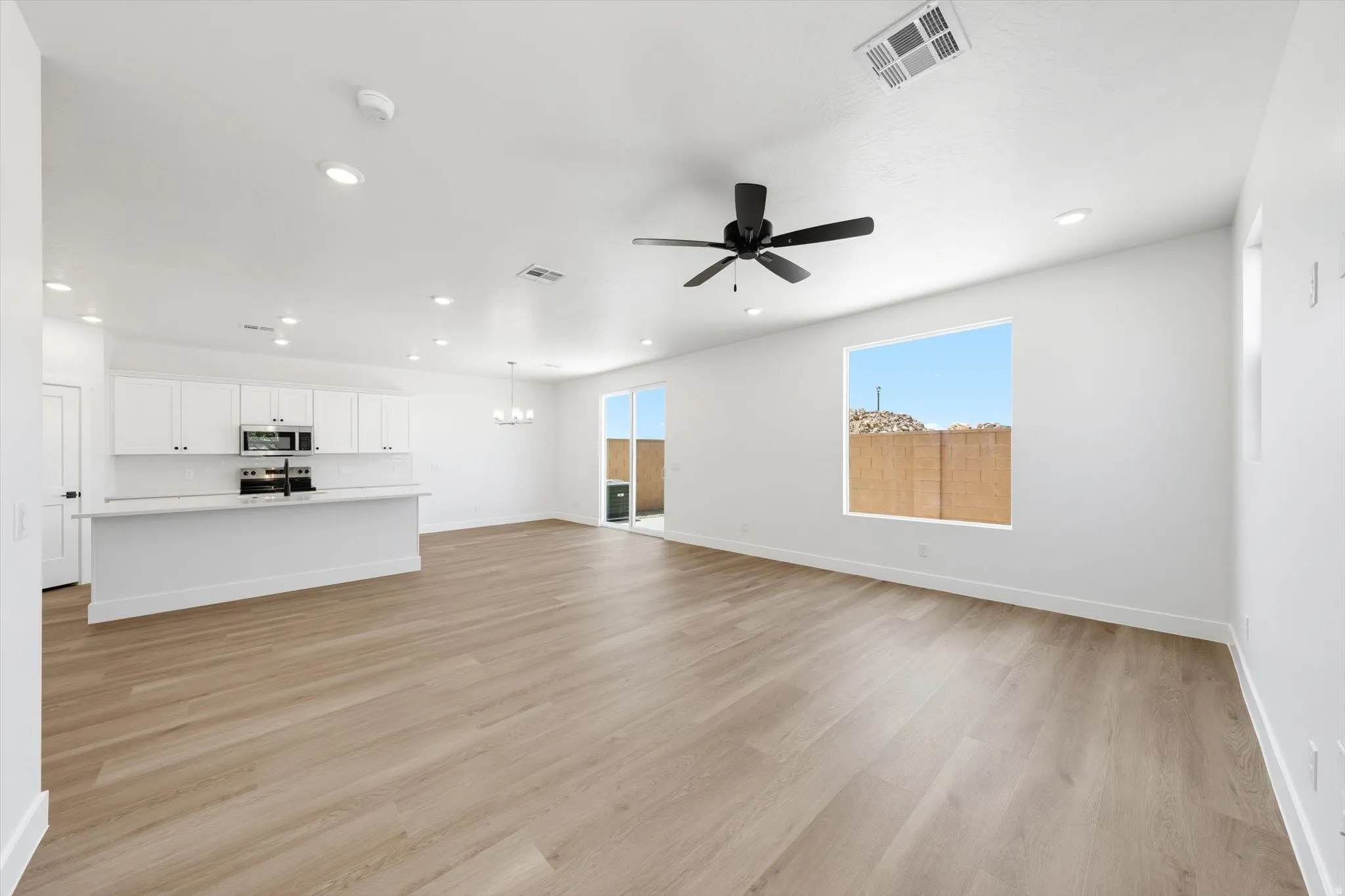 Open-concept living space with wood-finish flooring, recessed lighting, and a modern ceiling fan