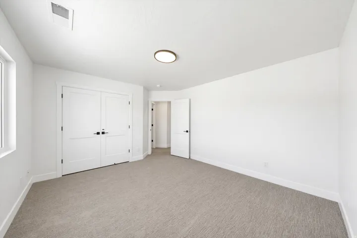Recessed lighting, light-toned carpet, ample natural light, bright white walls, and a contemporary ceiling fixture