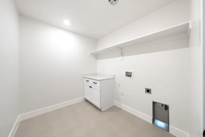 White cabinetry with black hardware, stone-finish countertop, recessed lighting, and wall-mounted shelving
