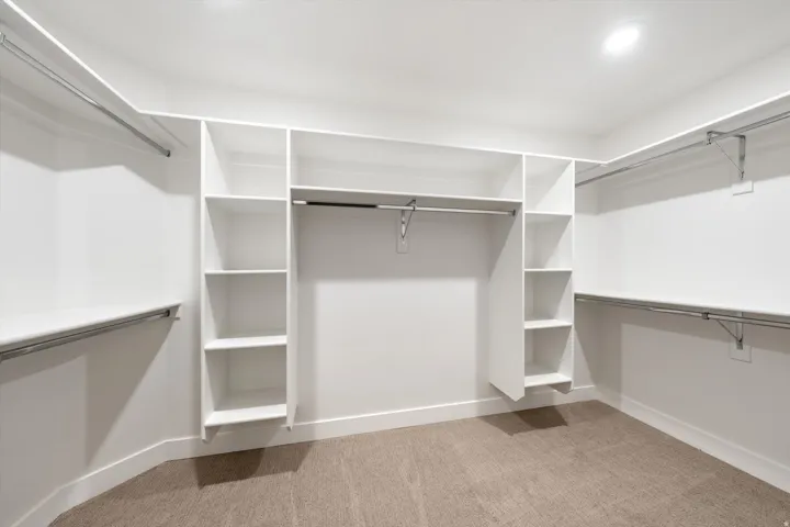 Built-in shelving, hanging rods, recessed lighting, and carpet flooring