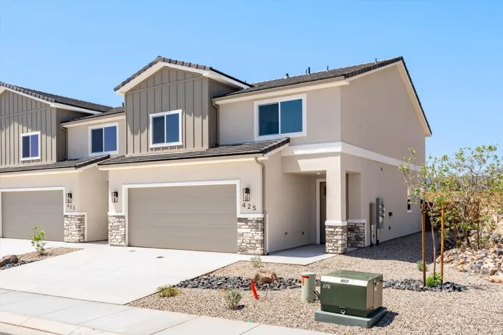 Two-story residence featuring a garage, stucco exterior, stone accents, and a front entry