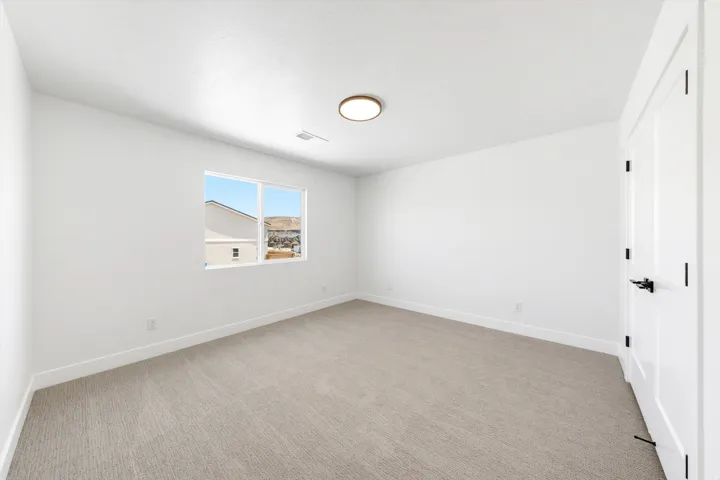 Neutral tone carpet flooring, white painted walls, a flush-mount ceiling light fixture, and a window with a mountain backdrop