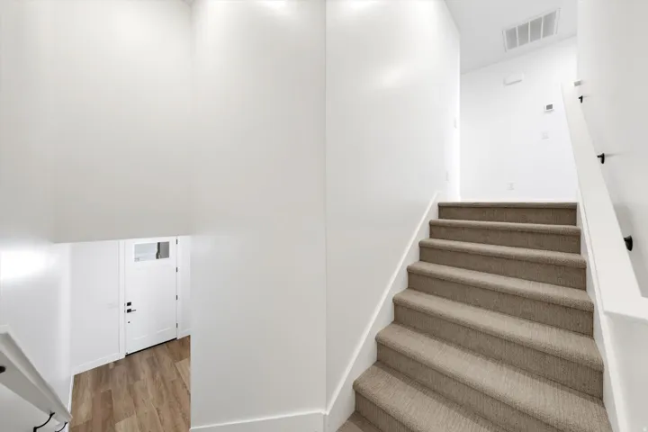 Carpeted staircase with white risers and handrails