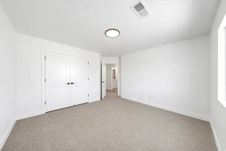 Neutral-toned carpet flooring, white walls, and a flush mount ceiling light fixture