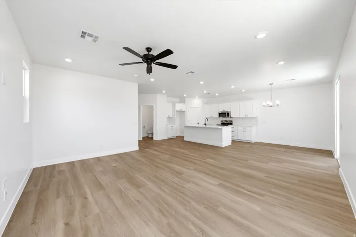 Expansive open-concept living area with wood-finish flooring, recessed lighting, and a ceiling fan