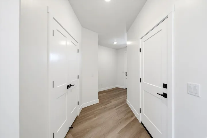 Entryway featuring wood-finish flooring, white paneled doors, and black hardware