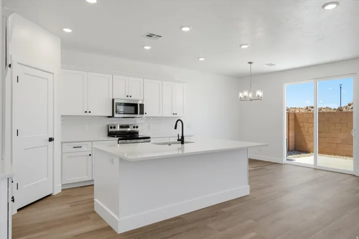 Kitchen featuring white cabinetry, a large central island with a solid surface countertop, stainless steel appliances, and wood-finish flooring