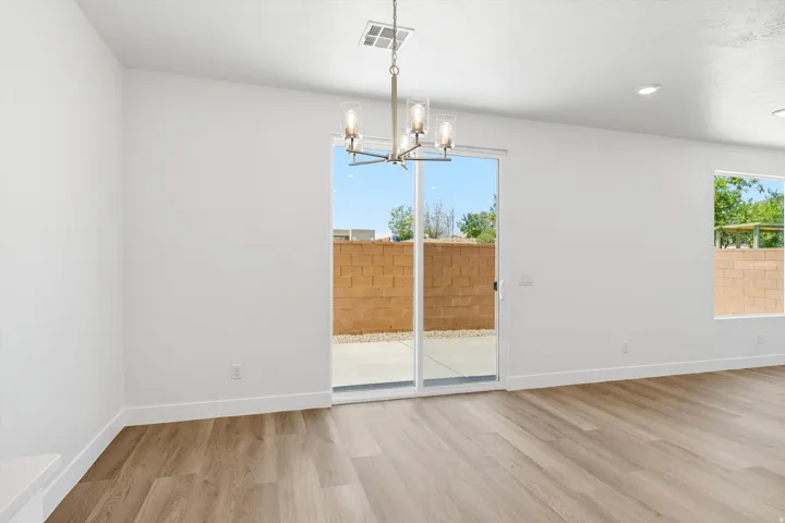 Sliding glass patio door, wood-finish flooring, recessed lighting, and a modern chandelier