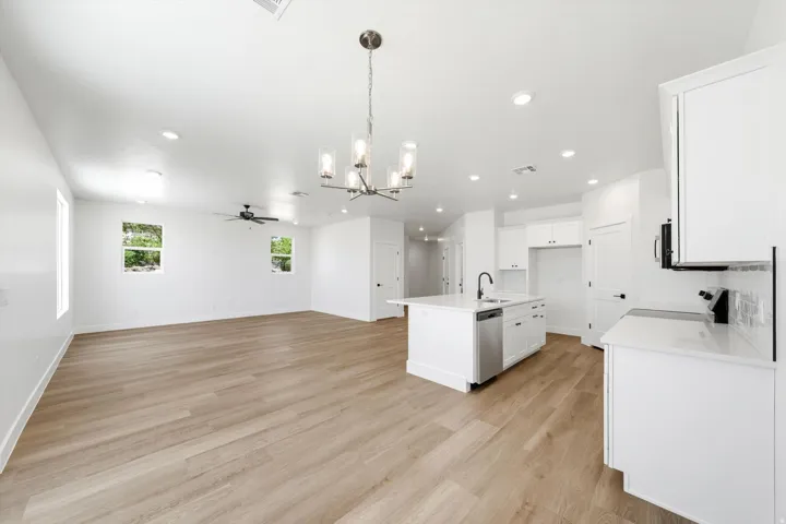 Open-concept living space with wood-finish flooring, recessed lighting, a ceiling fan, and white walls
