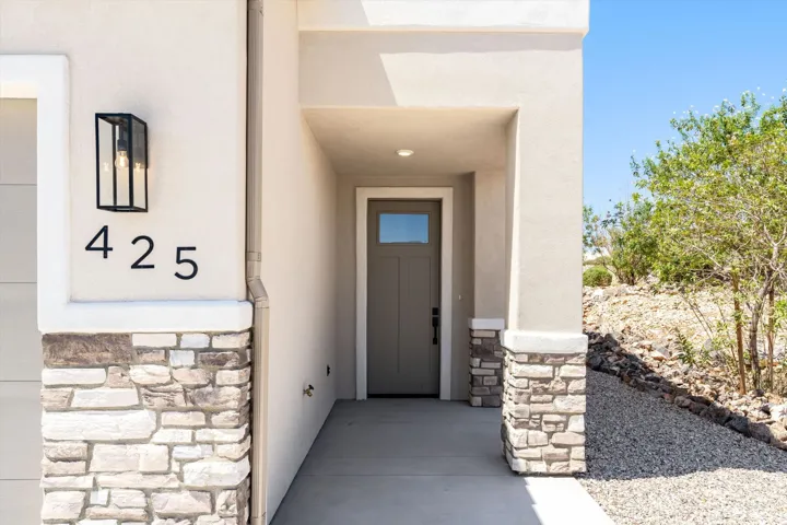 Stucco exterior featuring stacked stone accents, covered entry, and a contemporary front door with an integrated window