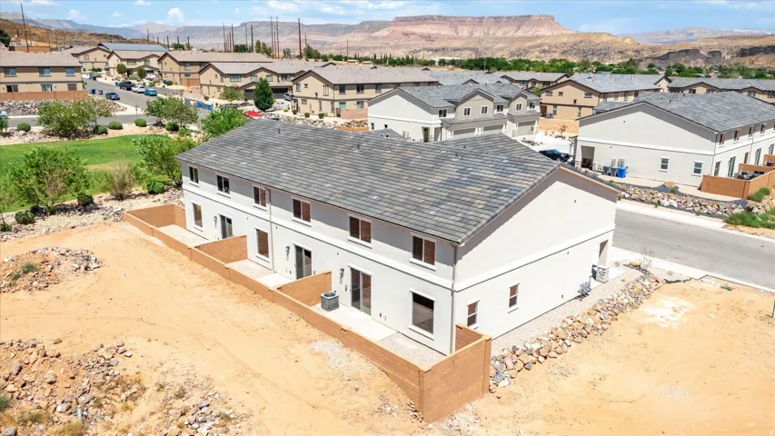 Multi-level residential building featuring a gray shingle roof and light-colored stucco exterior