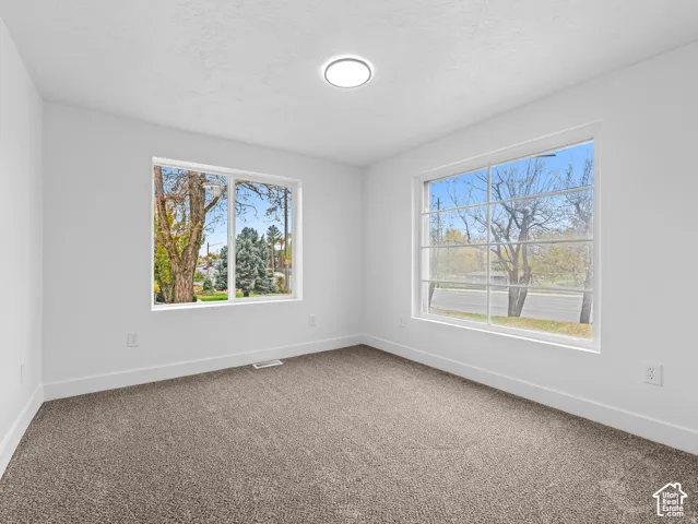 Wall-to-wall carpeting, white walls, and a flush-mount ceiling light