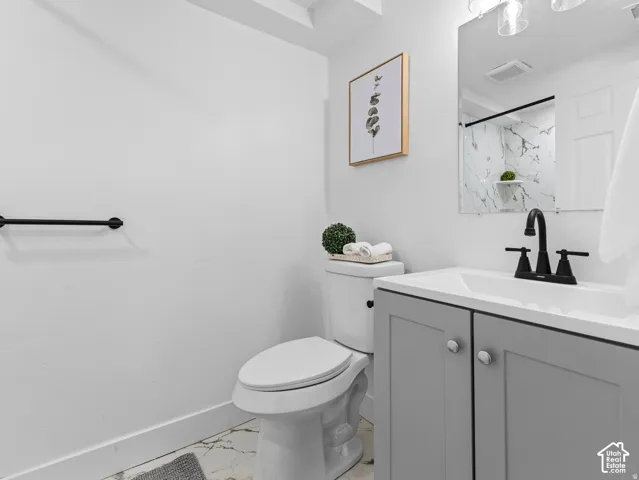 Bathroom featuring a gray vanity with a white countertop and integrated sink, matte black faucet, and patterned tile flooring