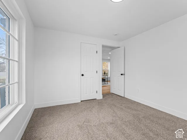 Bright interior space featuring a grid-pattern window, white paneled doors with black hardware, recessed ceiling lighting, and soft gray carpet