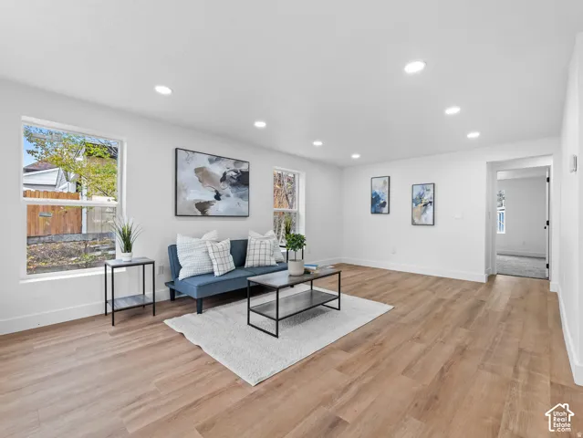Recessed ceiling lighting, multiple windows, wood-finish flooring, and white painted walls