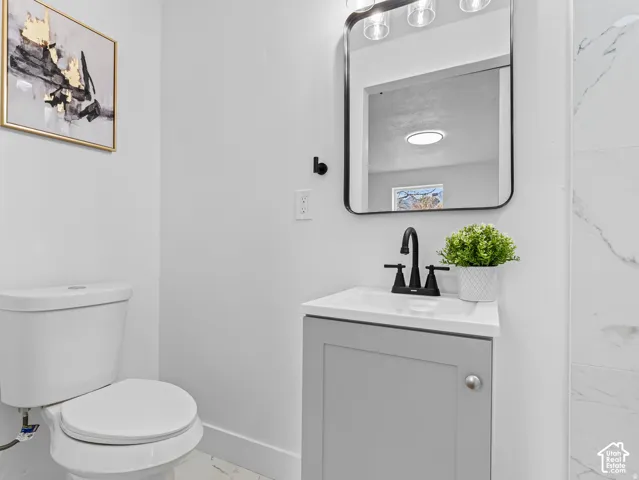 Gray vanity with integrated white sink, matte black faucet, and frameless mirror