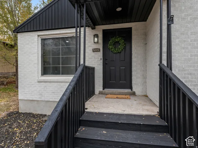 White brick exterior with black trim, paneled front door, and a black exterior light fixture