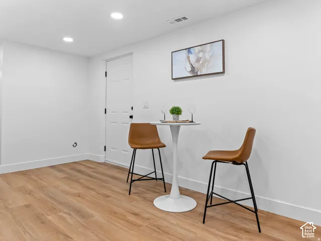 Recessed lighting illuminates the space, featuring wood-finish flooring and crisp white walls