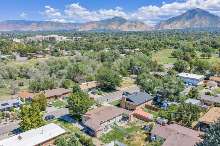 Aerial perspective showcasing residential properties with surrounding mature trees and distant mountain ranges