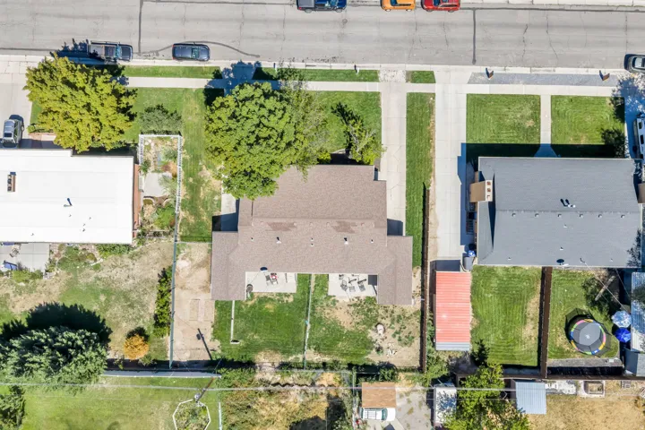 Gable roof with asphalt shingles, concrete driveway, and established trees